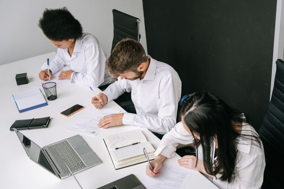 Diverse team working together in a sleek office with laptops and notebooks.